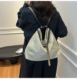 Rear view of a vintage soft leather tote bag with brown straps worn over a black coat