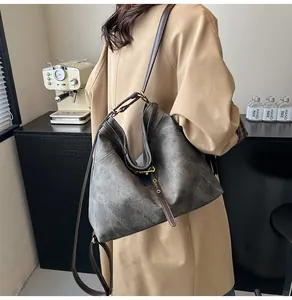 Detail of vintage large capacity tote bag with brown leather straps on a khaki trench coat