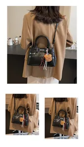 Détail du sac Kelly noir brillant avec ferrures argentées et charm ours en peluche