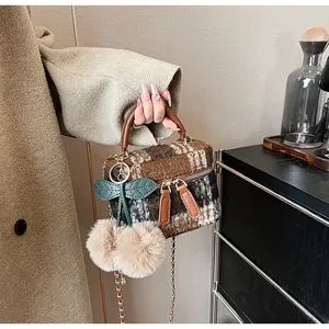 Detail van wollen geruite emmertas met kersen pluche hanger en gouden ketting