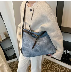 Detail of grey-blue vintage tote bag with deep brown leather straps and brass hardware