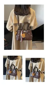 Détail du sac Kelly marron avec fermoir rotatif argenté et surpiqûres blanches contrastées