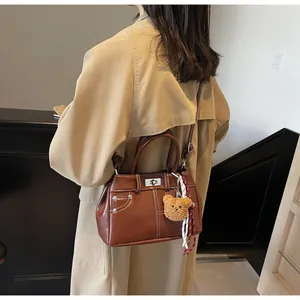 Détail du sac Kelly en cuir marron avec surpiqûres blanches et fermoir rotatif argenté