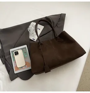 Vista piatta della borsa tote in pelle scamosciata marrone scuro con manici rinforzati