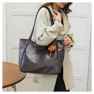 Vista dettagliata della borsa tote in pelle vintage marrone scuro con logo e orsetto