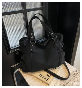 Gros plan d'un sac cabas noir avec rivets argentés et bandoulière réglable sur marbre