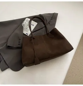 Macro della borsa tote in pelle scamosciata marrone scuro con texture opaca e ciondolo decorativo