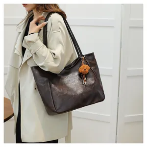Dettaglio della borsa tote marrone vintage con trama metallica e ciondolo a forma di orso