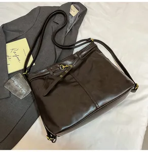 Detail of dark brown leather tote bag with side metal buckles and textured finish