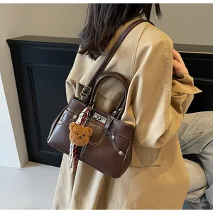 Détail du sac Boston marron café avec surpiqûres blanches et charme d'ours en peluche