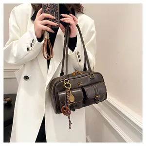 Close-up of retro brown Boston bag featuring dual front pockets and tennis racket charm
