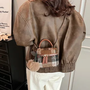 Mini geruite wollen emmer tas met gouden ketting en kersen hanger op bruin jasje