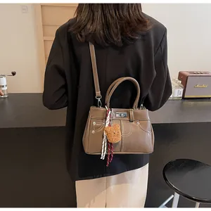 Détail d'un sac à main vintage en cuir marron avec fermoir argenté et petit ours
