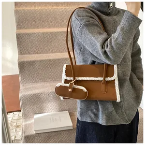 Détail d'un sac porté épaule en cuir marron avec bordure en peau lainée blanche et mini pochette