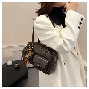 Detail view of coffee brown retro Boston bag on a model featuring gold logo and tennis pendant