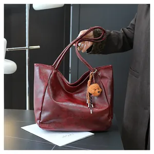 Dettaglio della borsa tote bordeaux vintage con trama cerata e ciondolo a orsetto