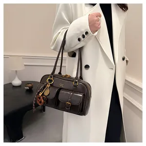 Close-up of retro brown Boston bag with golden buckles and decorative tennis charms