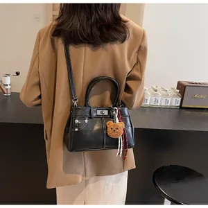 Détail du sac en cuir noir avec couture poche denim et fermoir rotatif argenté