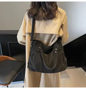 Grand sac fourre-tout gris foncé porté avec un trench beige dans un cadre moderne