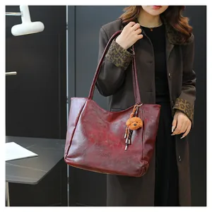 Dettaglio della borsa vintage rosso scuro con logo TonTon e ciondolo a cucciolo