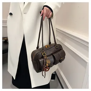 Detail of dark brown Boston bag with multi-pockets, golden buckles and decorative charms