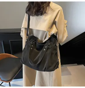 Détail d'un grand cabas noir en nylon montrant la texture plissée et la large bandoulière
