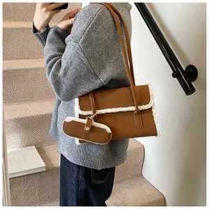Détail du sac bandoulière en daim marron avec bordure en polaire et petite pochette