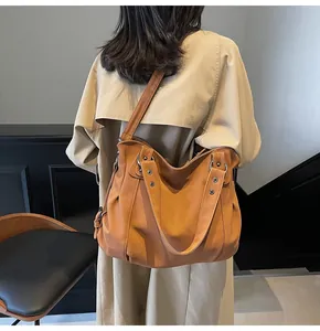Vue de dos d'un grand sac cabas en cuir camel avec rivets porté par un mannequin en studio