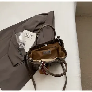 Détail de l'intérieur d'un sac cabas en cuir marron avec poche zippée et breloque