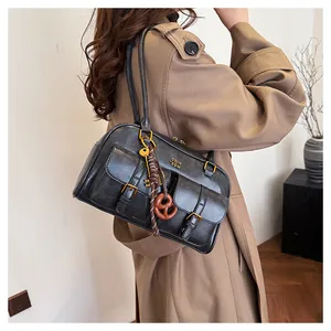 Detailed view of black leather Boston bag featuring gold buckles and creative key charm
