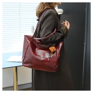 Dettaglio borsa tote bordeaux vintage in pelle martellata con ciondolo a orsetto