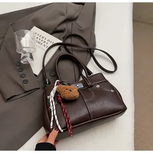 Détail du sac à main en cuir marron foncé avec surpiqûres contrastées et fermoir argenté