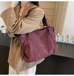 Mannequin portant un grand sac cabas violet foncé en cuir mat avec détails de rivets