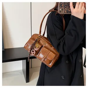 Detail shot of brown vintage Boston bag with brass buckles and decorative charms on a model