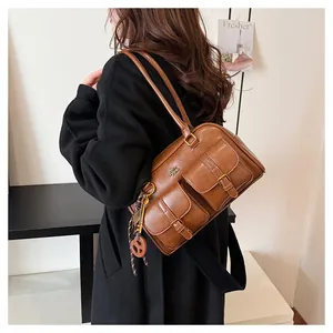 Brown vintage Boston bag with dual pockets and pretzel charm worn by a model