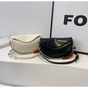 Detalle de bolsos de media luna con cadenas plateadas y adornos de cuentas de ámbar