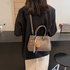 Sac Kelly vintage marron avec breloque ours et foulard en soie porté par un mannequin