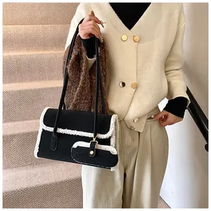Détail du sac à bandoulière noir avec bordure en fausse fourrure blanche et mini pochette