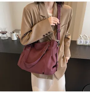 Grand sac fourre-tout bordeaux porté en bandoulière dans un café moderne