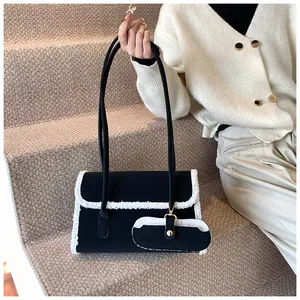 Détail du sac à bandoulière noir avec bordure en peluche blanche et mini pochette assortie