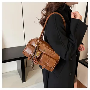 Close-up of vintage brown leather Boston bag featuring two front buckled pockets and charms