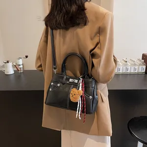 Sac Kelly noir tendance avec surpiqûres blanches, breloque ours et détail de foulard en soie