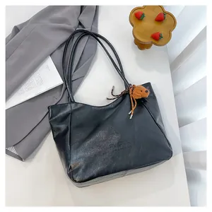Dettaglio borsa tote in pelle PU nera con logo Tonton goffrato e ciondolo orsetto marrone