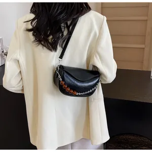 Detalle de bolso de silla en cuero plisado negro con cadena de cuentas de ámbar