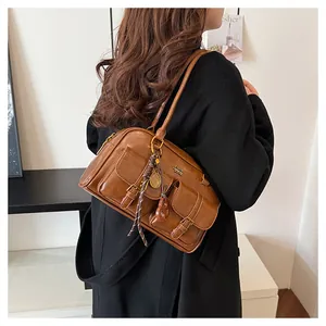 Detailed view of brown faux leather Boston bag with metal logo and buckle pockets