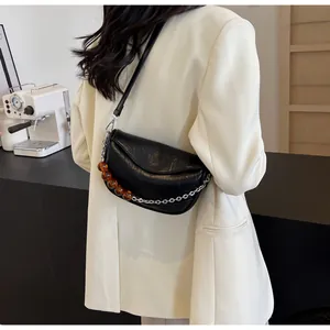 Detalle de bolso nube negro plisado con cadena plateada y cuentas de ámbar decorativas
