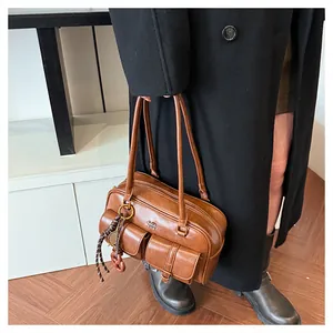 Close-up of brown vintage leather bag with utility pockets and rope keychain detail