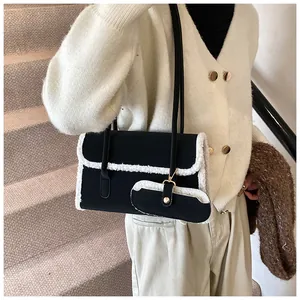 Détail du sac sous le bras noir avec bordure en laine blanche et mini pochette assortie