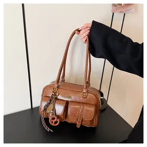 Detail of brown vintage Boston bag showing leather texture, front pockets, and metal logo