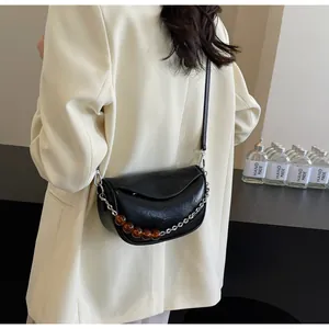 Detalle de bolso silla nube negro con textura plisada vintage y adorno de cadena